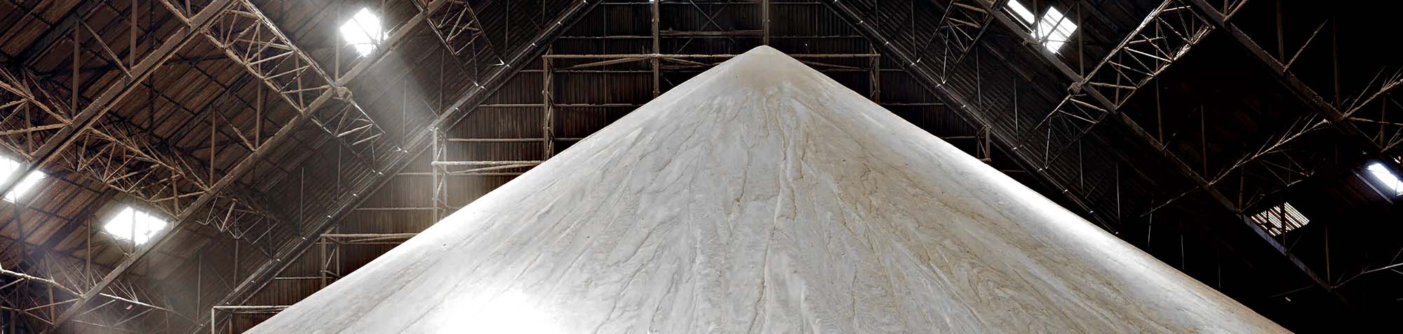 close up of Large pyramid-shaped mound of raw sugar inside a warehouse with beams of light