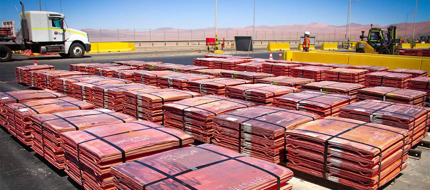 Bundled copper cathode pallets arranged in rows at a refinery yard.