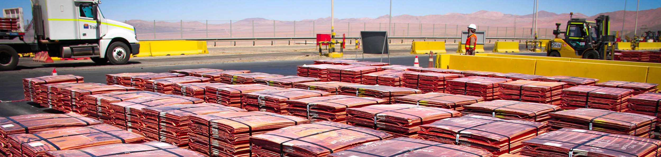 Bundled copper cathode pallets arranged in rows at a refinery yard.